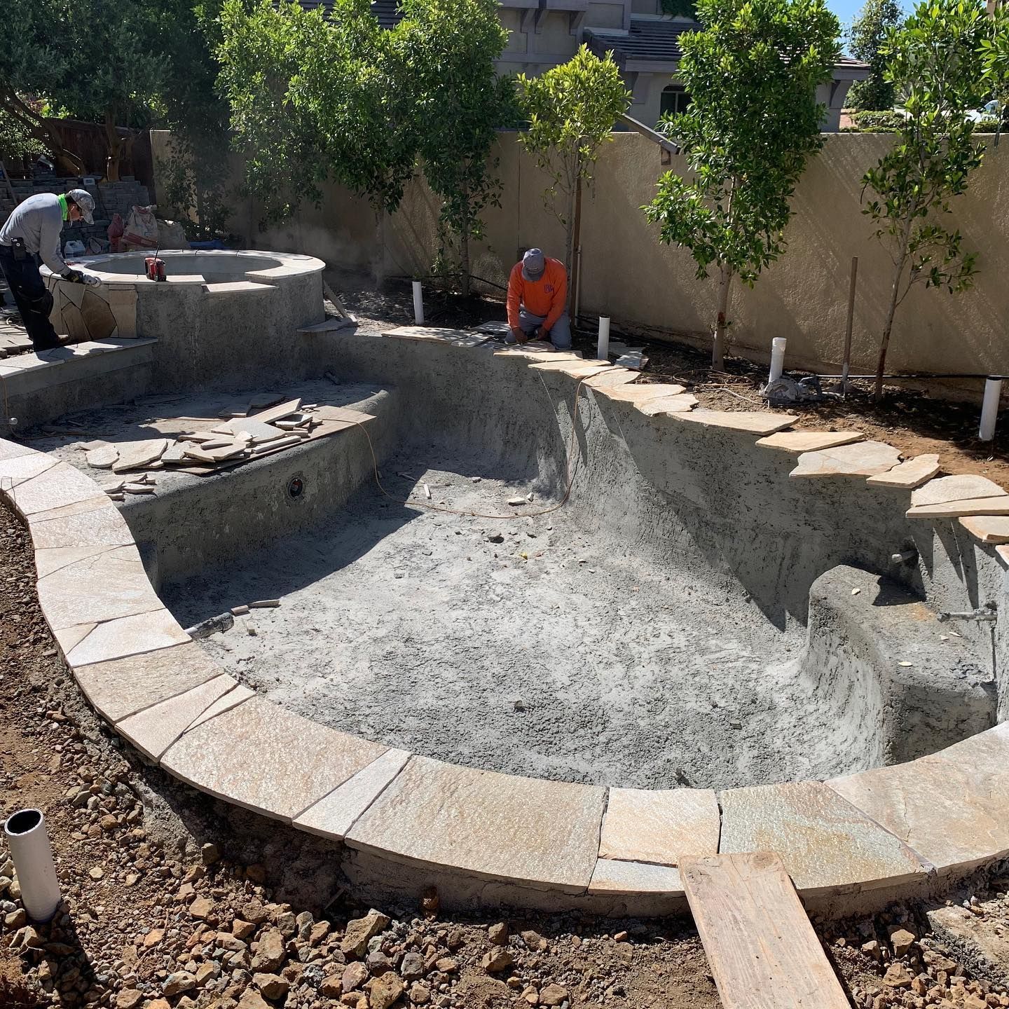 A man is working on a swimming pool in a backyard.
