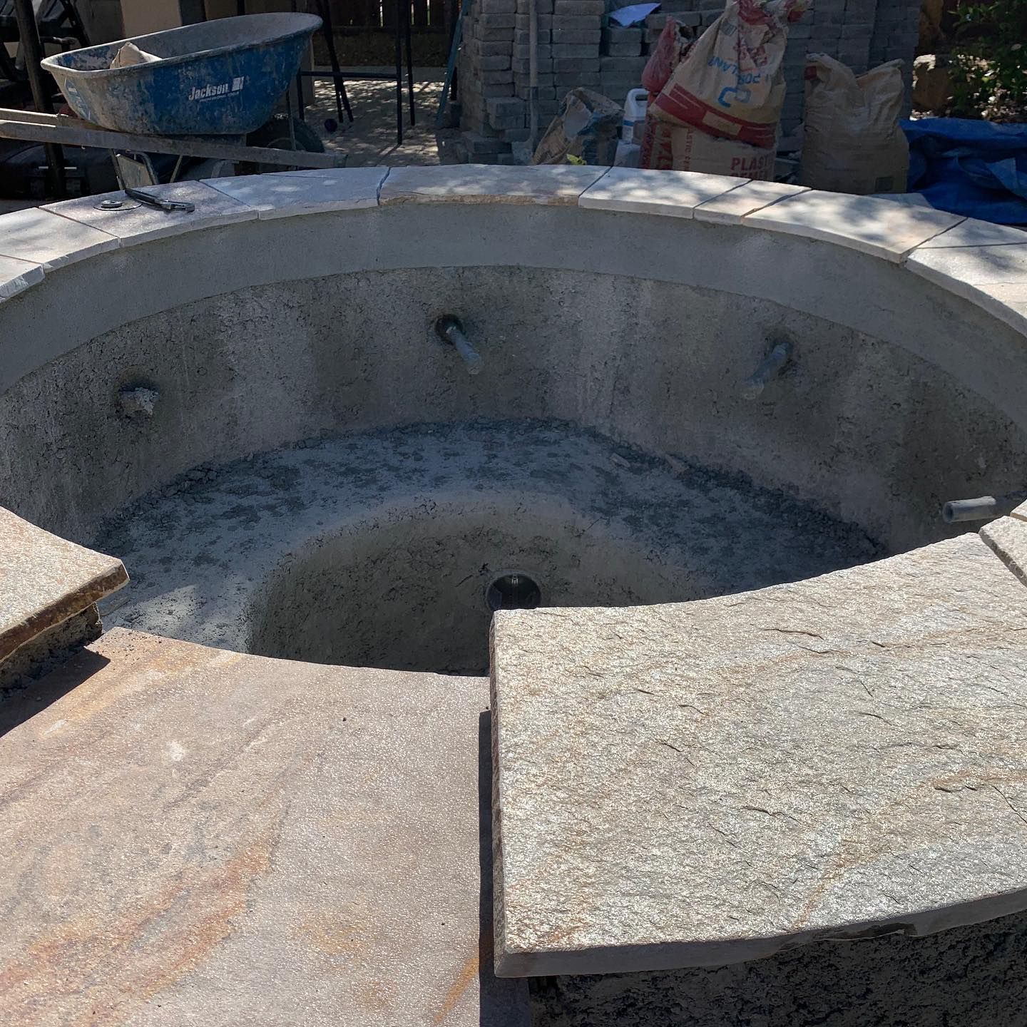 A concrete fire pit is being built in a backyard.