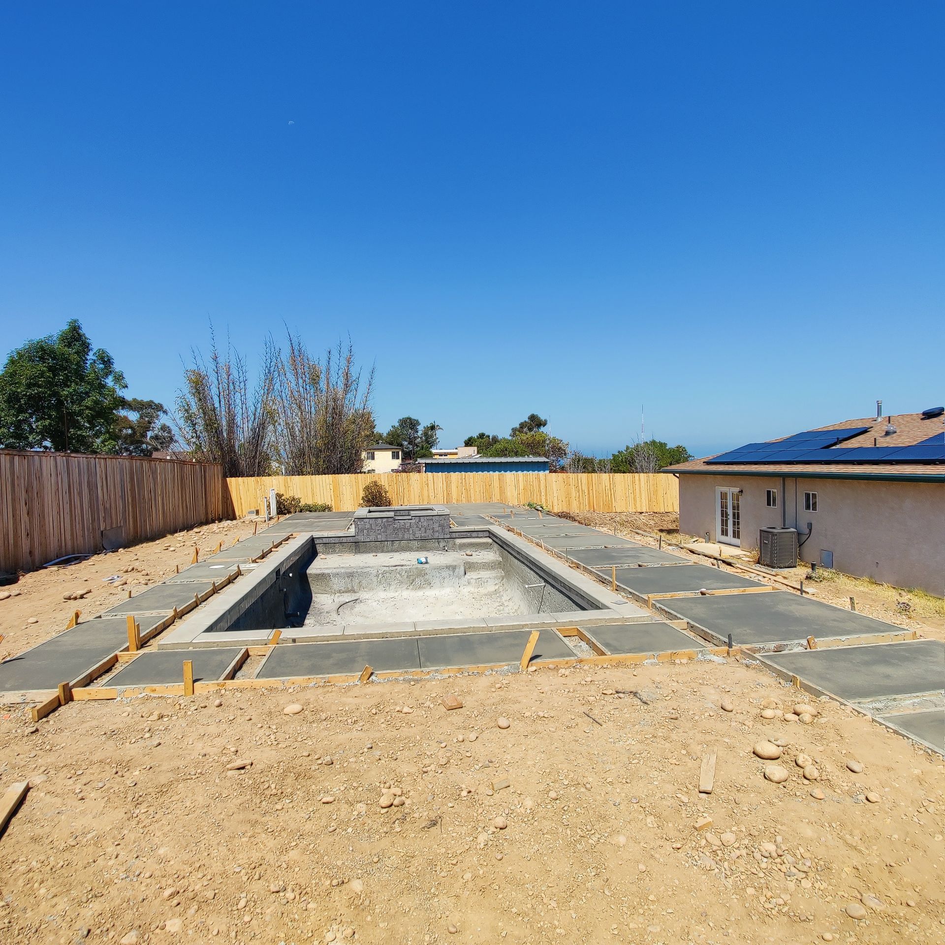 A swimming pool is being built in the backyard of a house