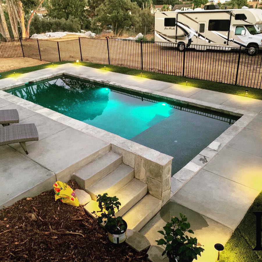 A large swimming pool with a rv parked in the background