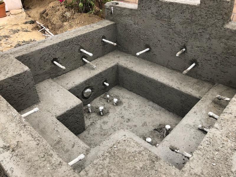 A concrete bathtub is being built in a backyard.