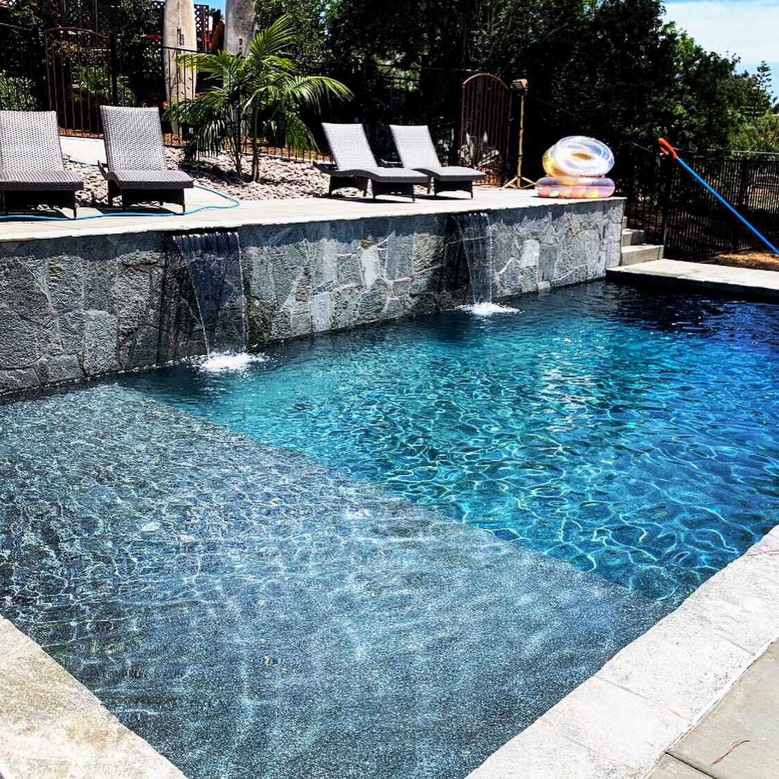 A large swimming pool with a waterfall in the middle