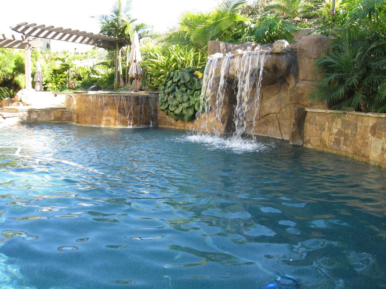 A large swimming pool with a waterfall in the background