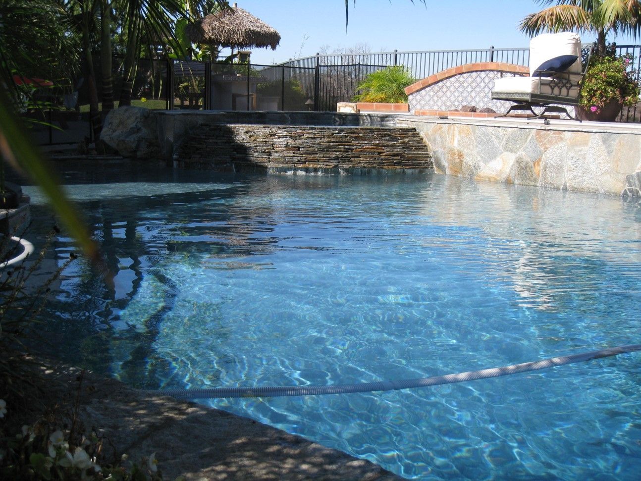 A large swimming pool with a chair and umbrella in the background