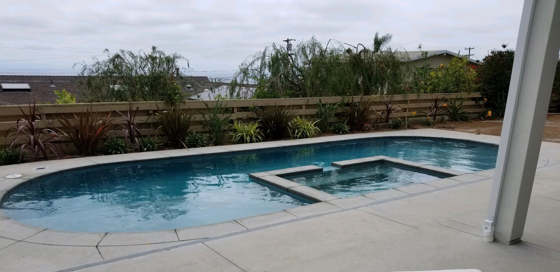 There is a large swimming pool in the backyard with a view of the ocean.