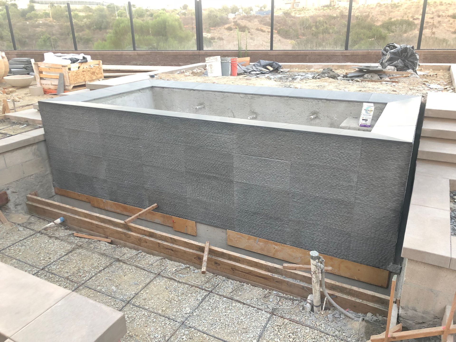 A large concrete pool is being built in a backyard.