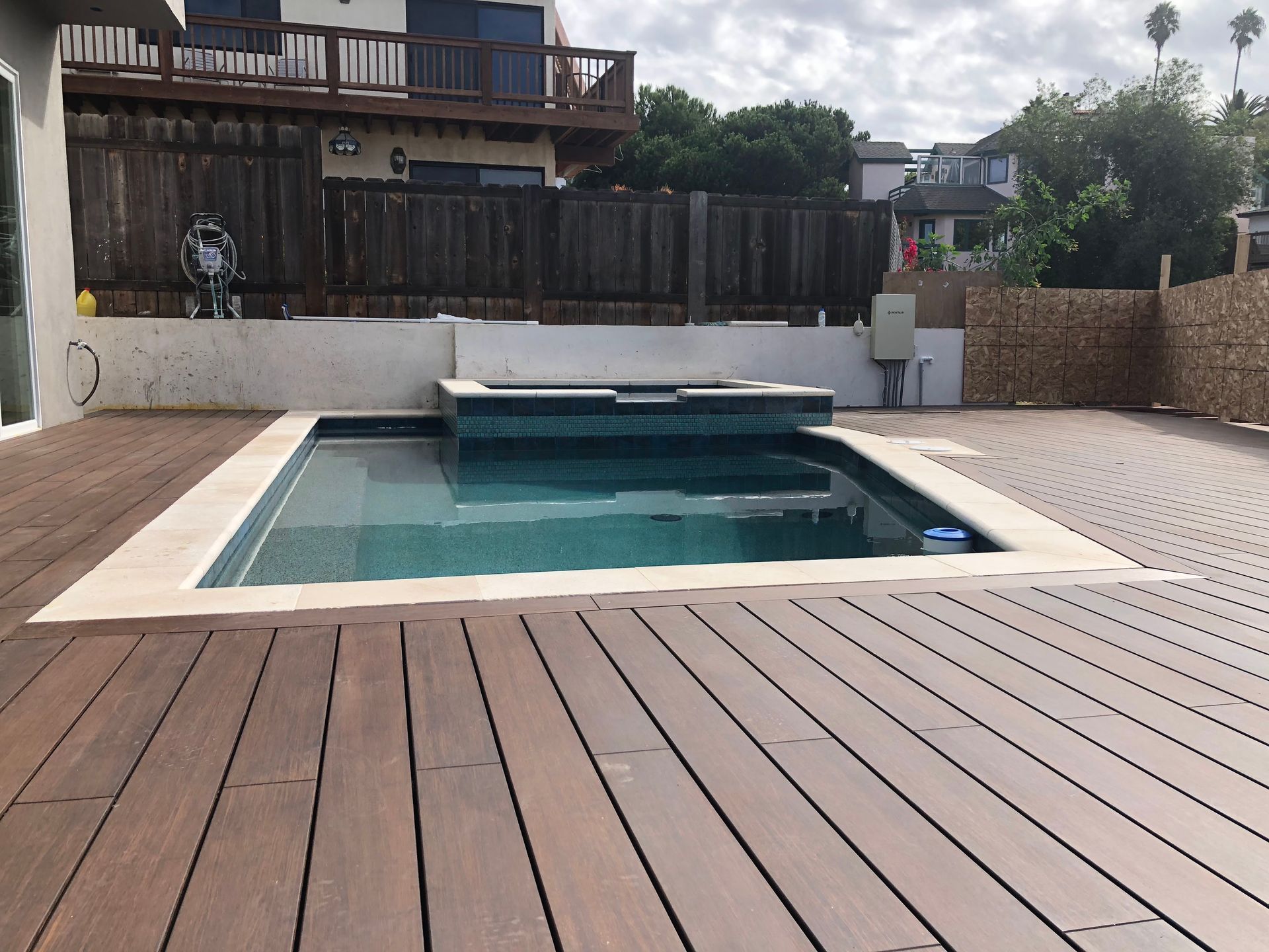 A large swimming pool is surrounded by a wooden deck