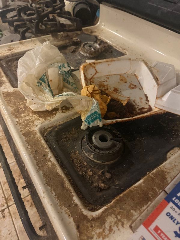 A dirty stove top with a bag of food on it.