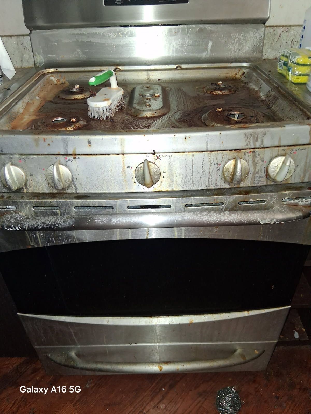 A dirty stove top oven with a brush on it.