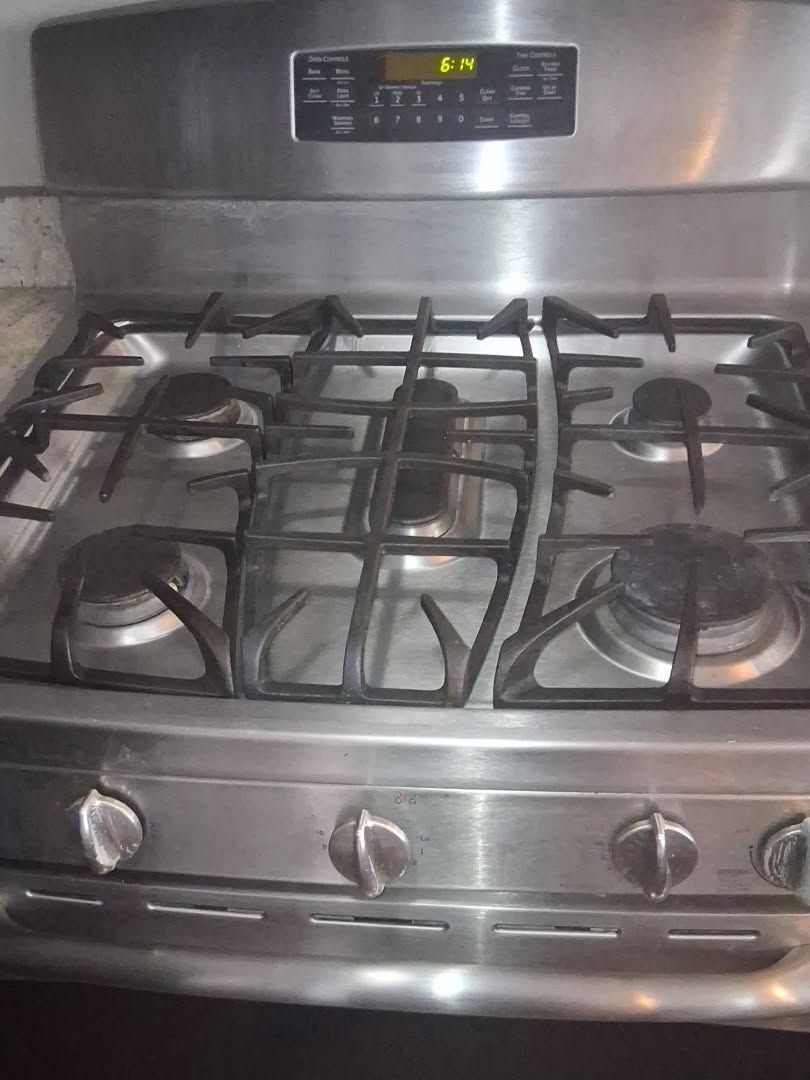 A stainless steel gas stove with four burners and a digital display