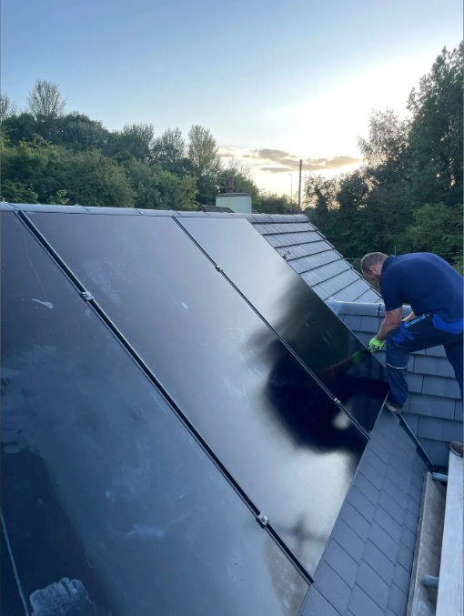 A man is working on a solar panel on the roof of a building.