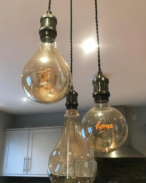Three light bulbs are hanging from the ceiling and one of them says home