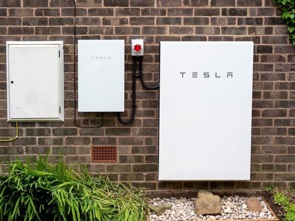 A tesla solar panel is mounted on a brick wall.
