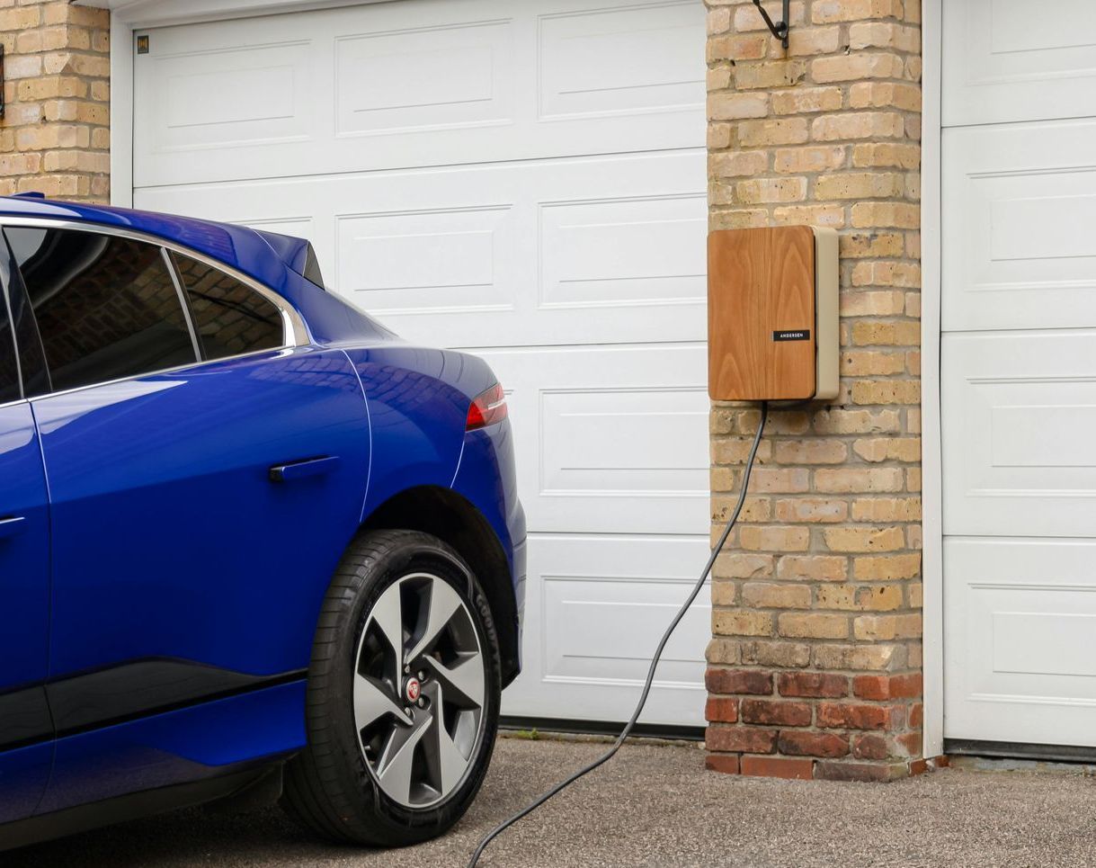 A blue electric car is being charged in a garage.