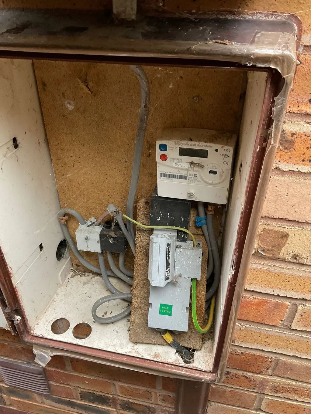 A meter is sitting inside of a box on a brick wall.