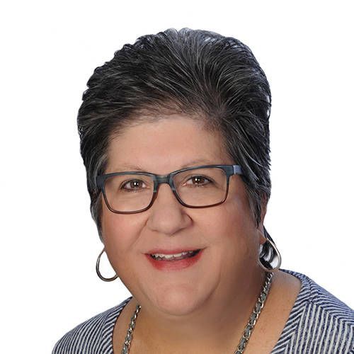 A woman wearing glasses and a striped shirt is smiling for the camera.
