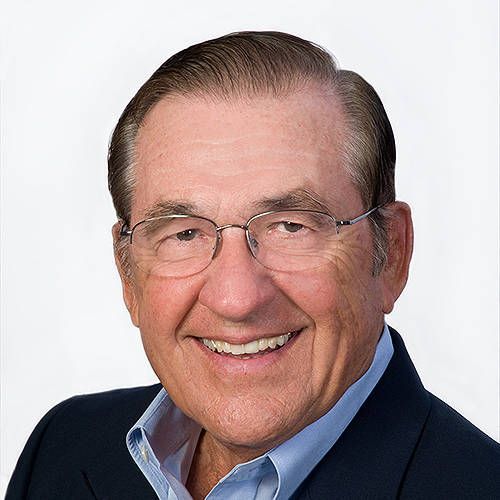 A man wearing glasses and a suit is smiling for the camera.