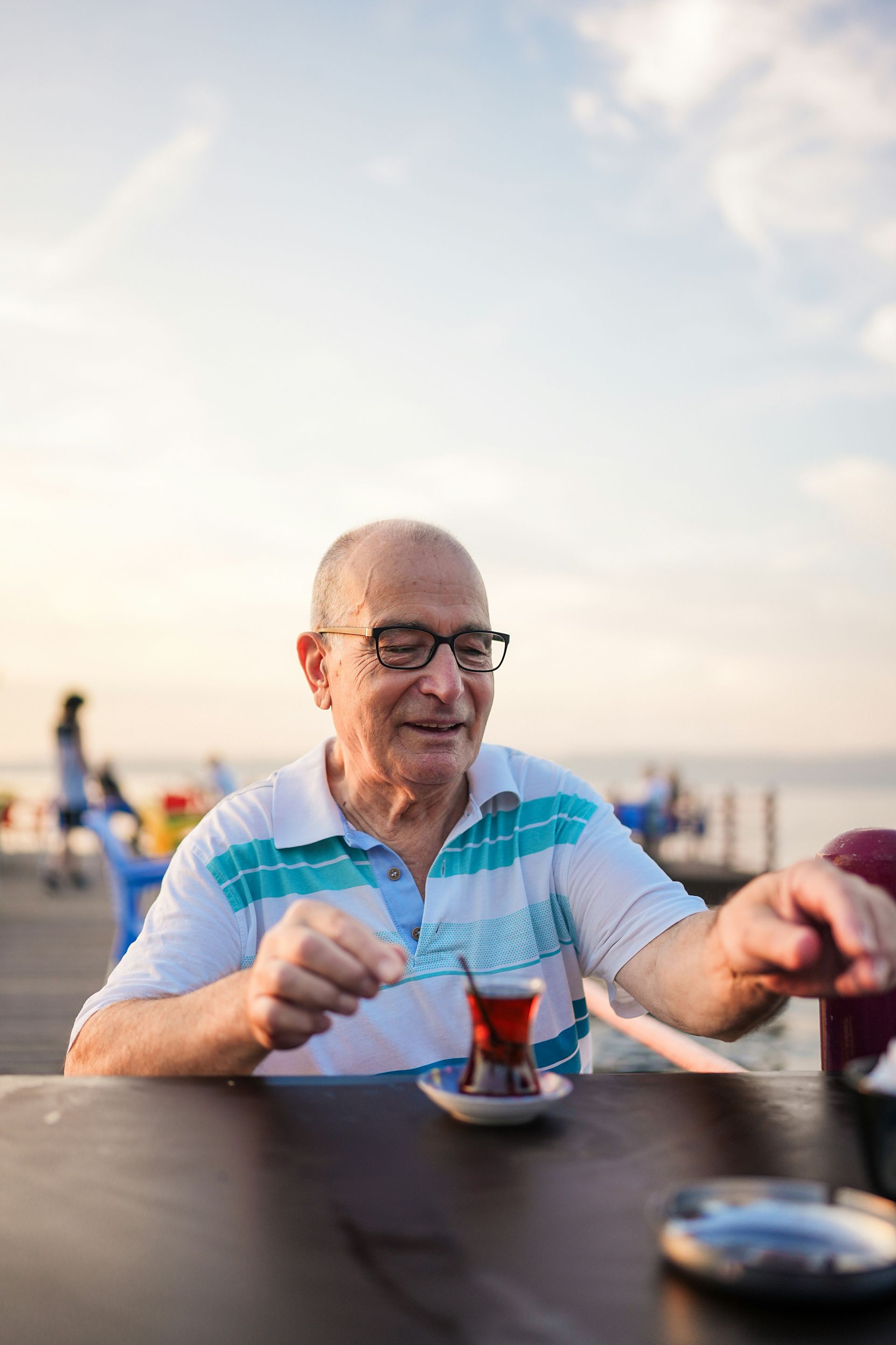 An elderly man is sitting at a table drinking tea.