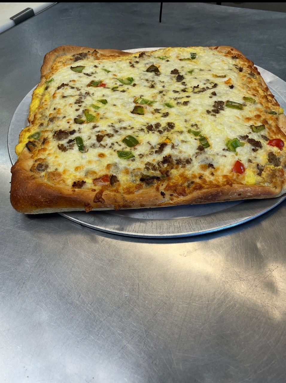 A pizza is sitting on a pan on a table.