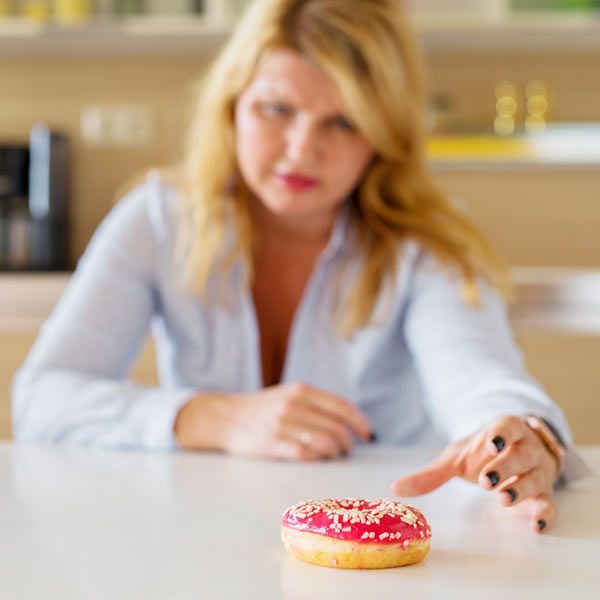 woman with a Cortisol Imbalance reaching for a doughnut because of a sugar craving