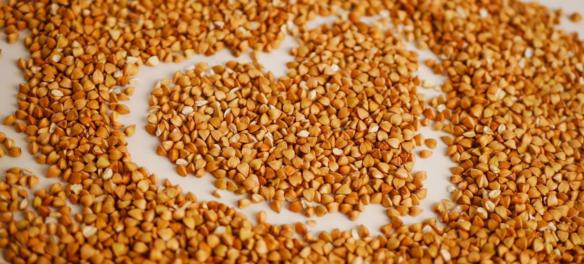 A pile of buckwheat grains on a white surface in the shape of a heart. Buckwheat Health Benefits