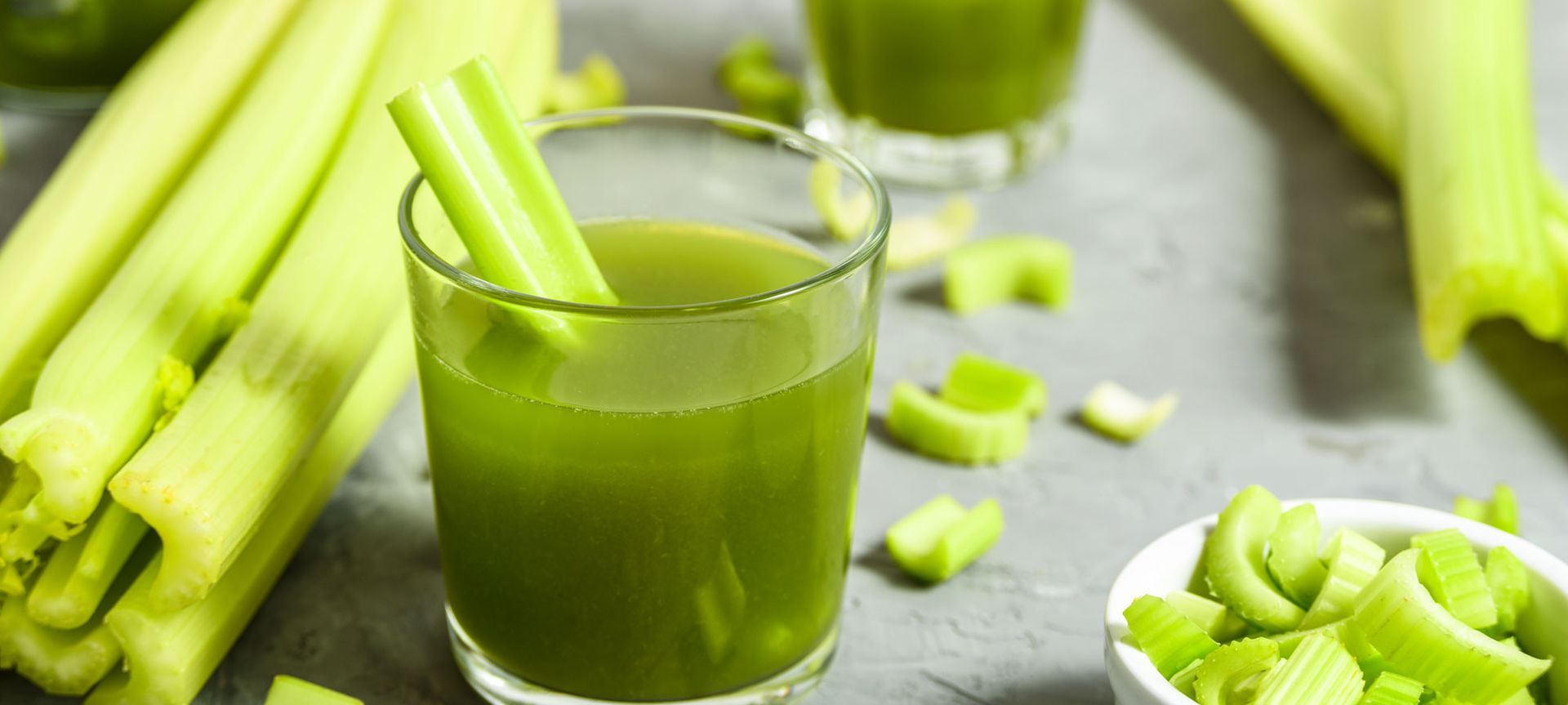 A glass of celery juice with celery sticks in it.