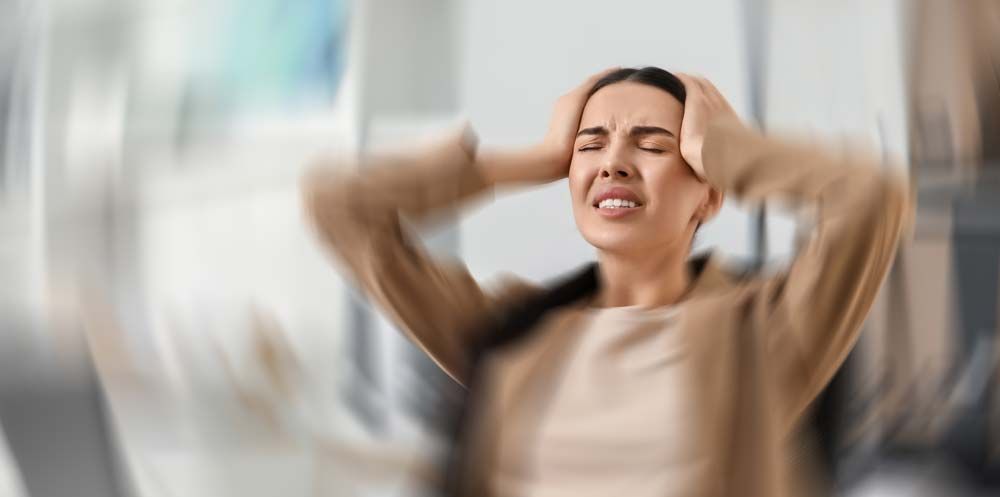 Woman with hands on head, reacting to Hormone Imbalance and Stress. Blurred background.