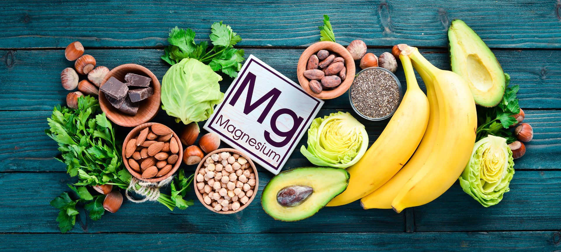 A variety of foods containing magnesium are on a wooden table highlighting the benefits of Magnesium.