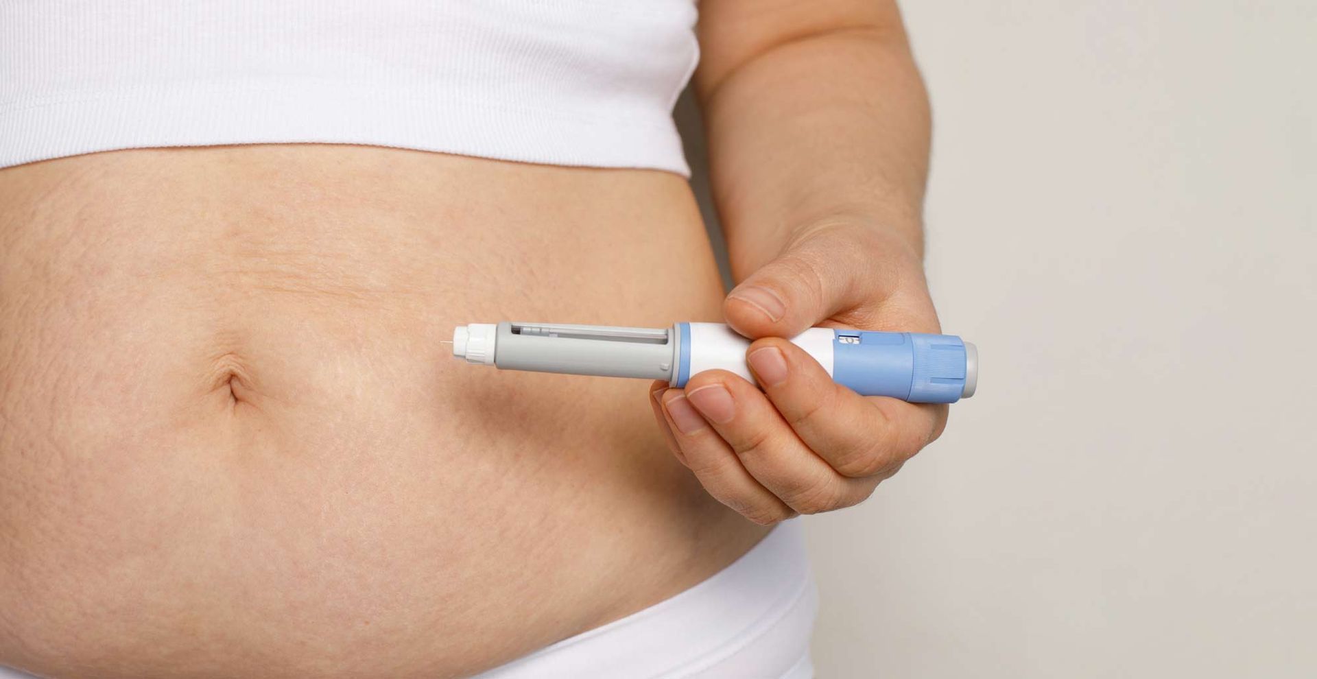 A woman is holding a syringe in front of her stomach. Natural Alternatives to Ozempic