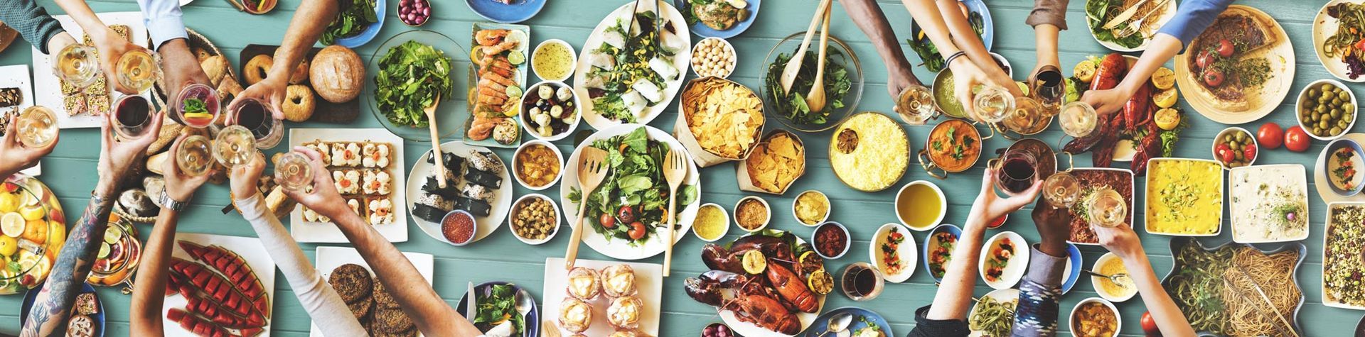 A group of people are sitting around a table filled with lots of food.