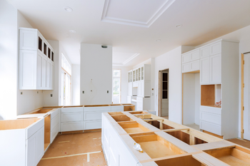 A kitchen under construction with white cabinets and wooden counter tops.