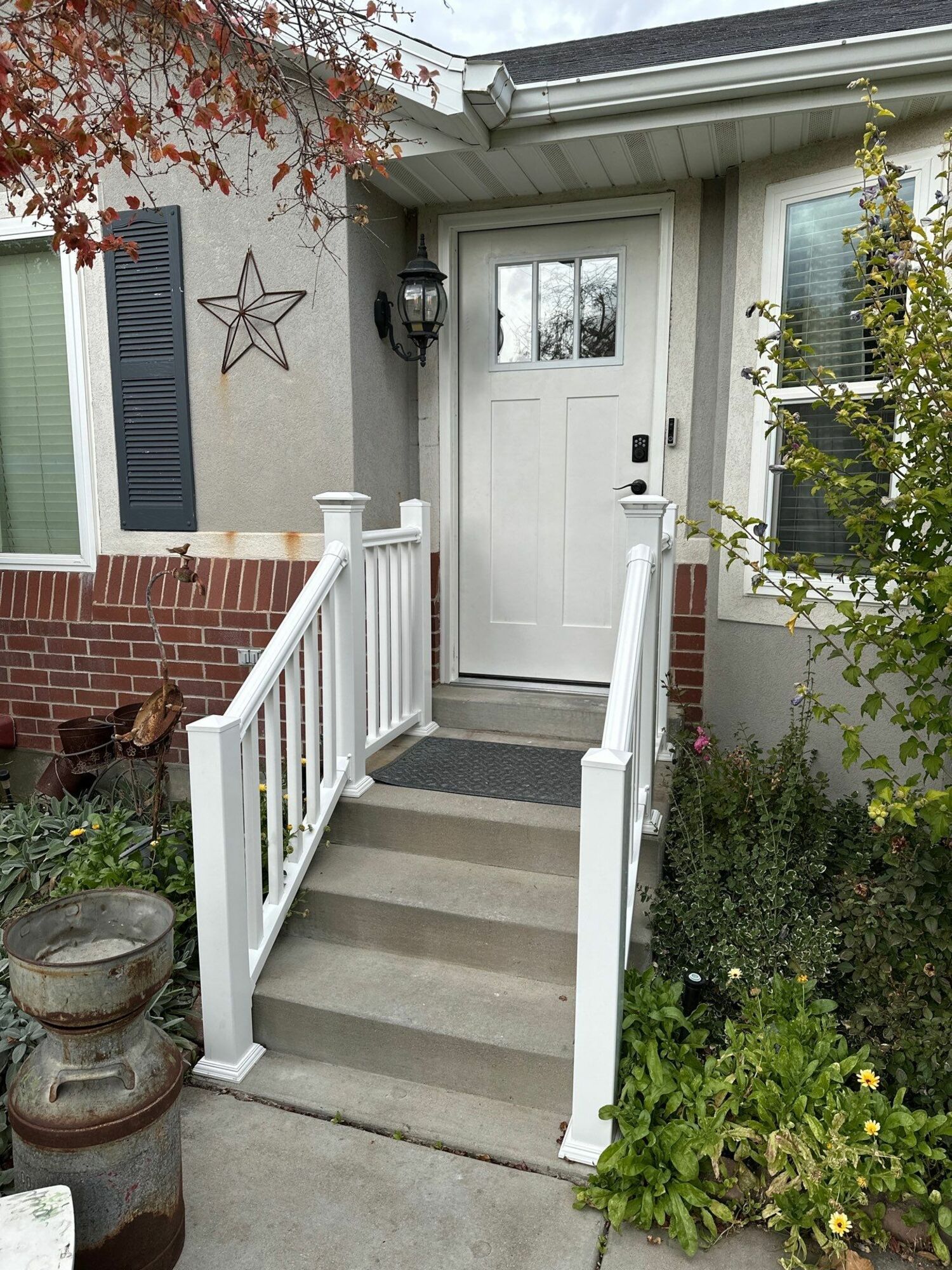 The front door of a house with a white railing and stairs leading up to it.