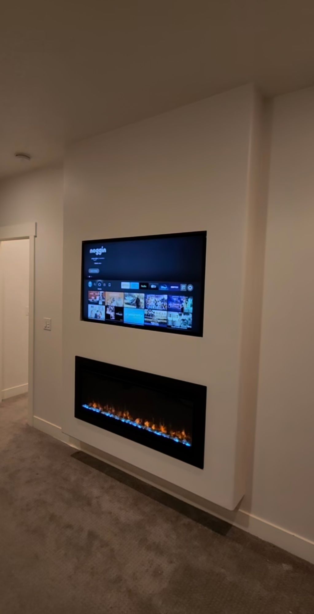 A living room with a fireplace and a flat screen tv mounted on the wall.