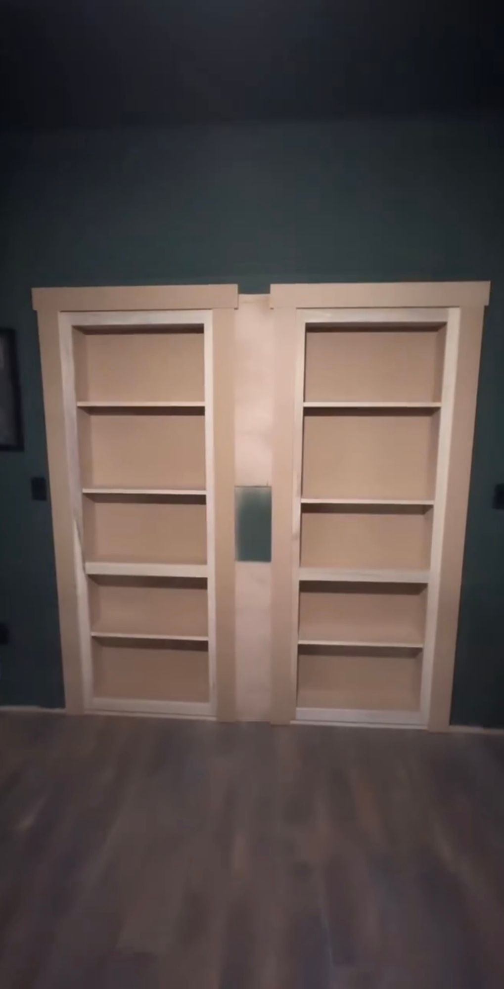 A pair of wooden shelves in a room with a green wall.