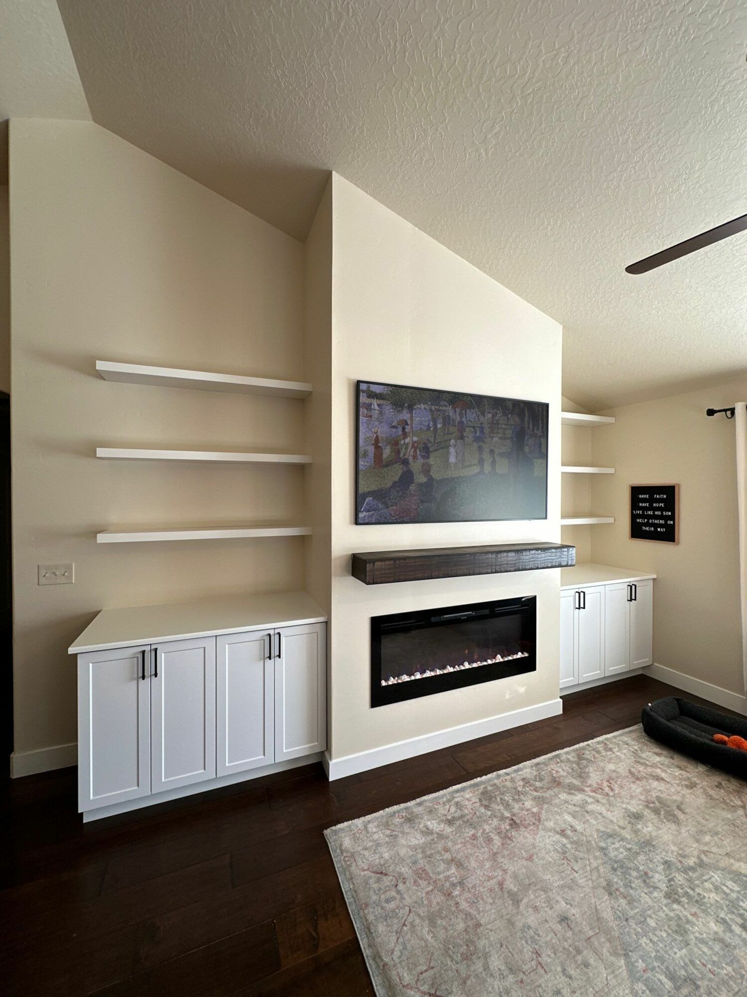 A living room with a fireplace , shelves , and a painting on the wall.