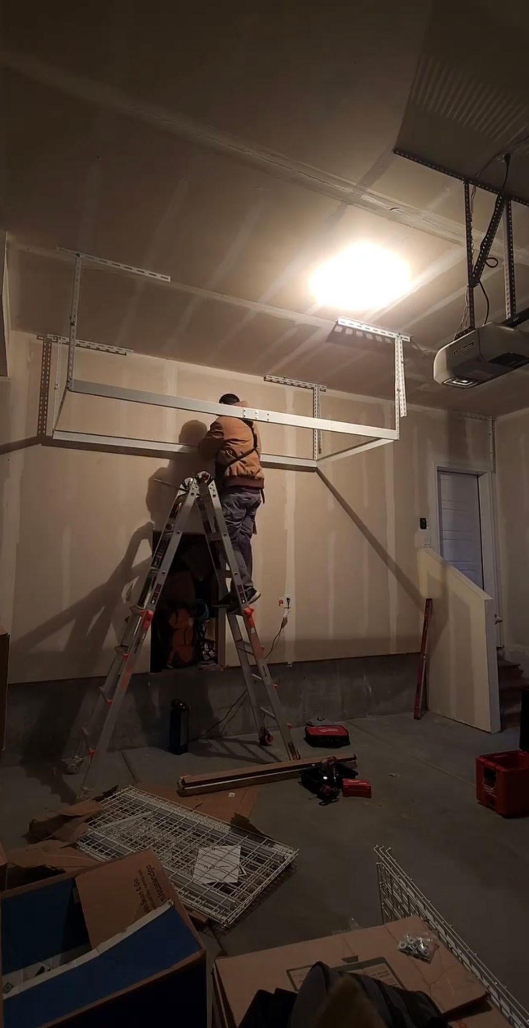 A man is standing on a ladder in a garage.