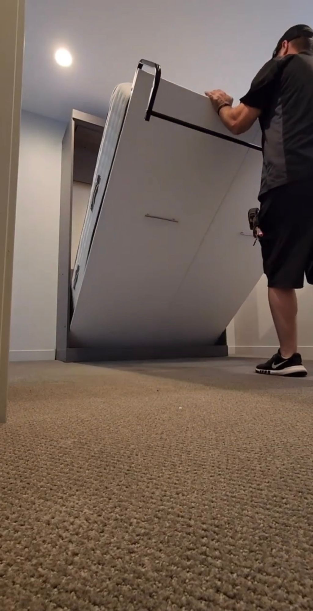 A man is lifting a bed into a wall mounted bed.