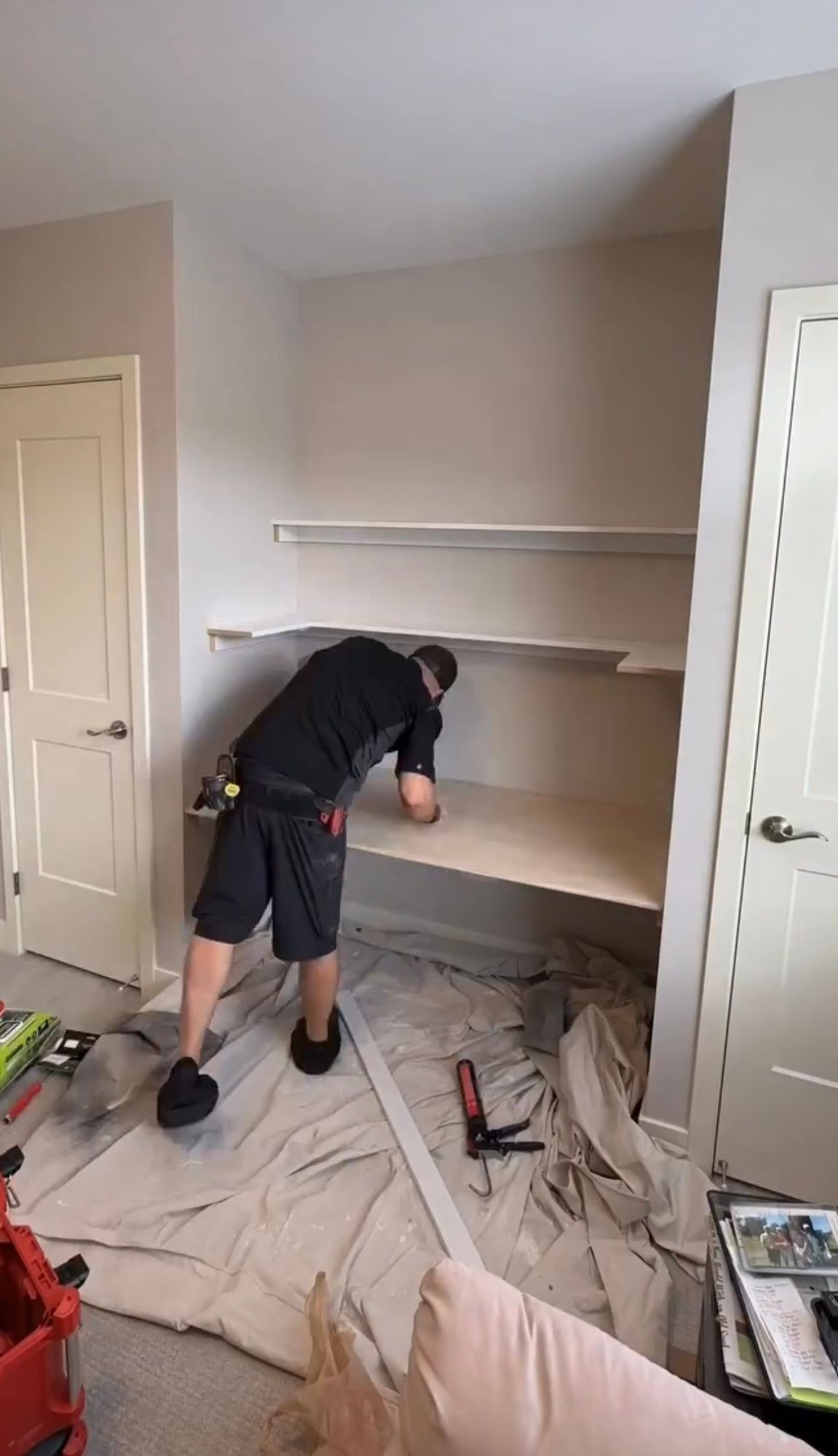 A man is working on a shelf in a room.