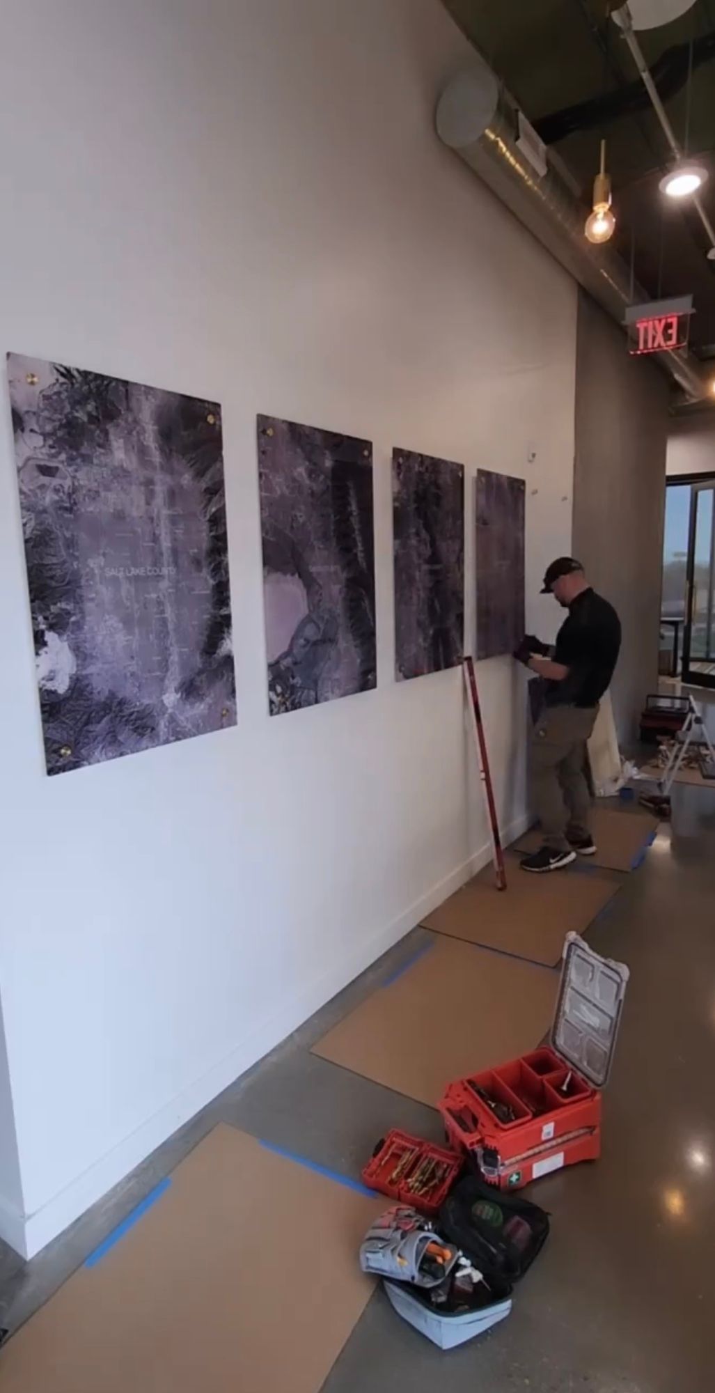 A man is working on a painting on a wall in a room.