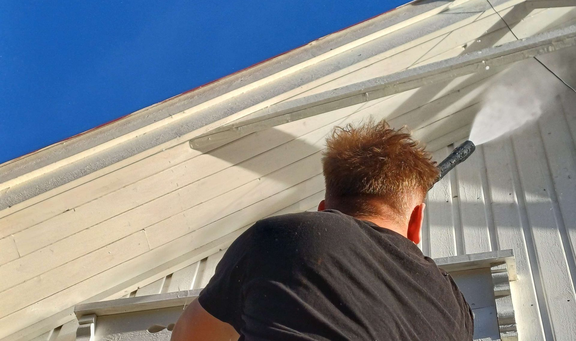 A roof with brown tiles and a chimney, next to a grassy hill and dirt path.