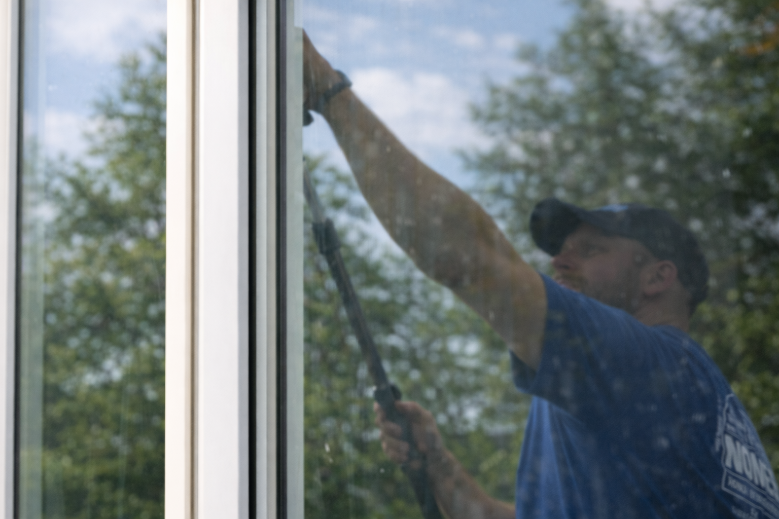 White house with dark blue roof, windows, chimney, and roof ladder.