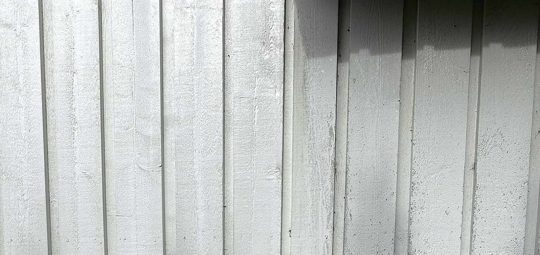 Vertical ribbed concrete wall with a visible difference in color on the right side.