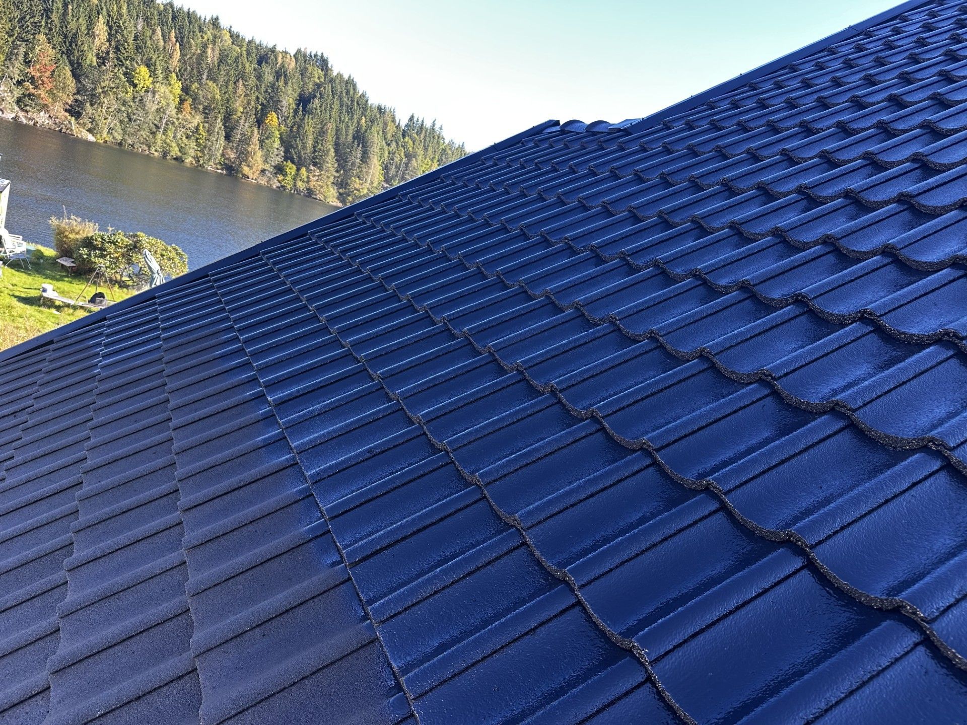 Mørk blå-svart fornyet tak med vann i bakrunnen