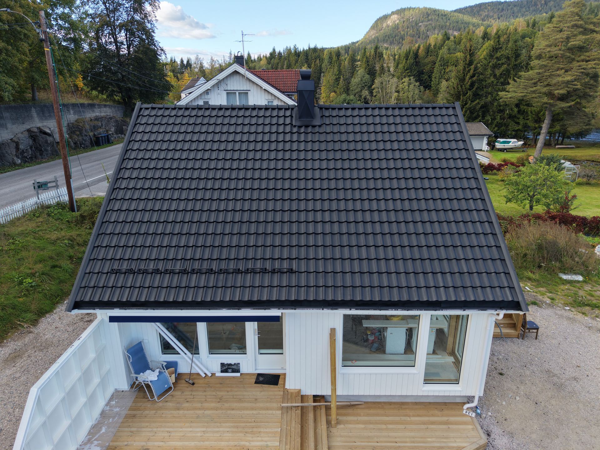 Brown tiled roof, top-down view; residential area with green foliage and asphalt road in the background.