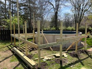 Partially built wooden above-ground pool frame in a grassy yard