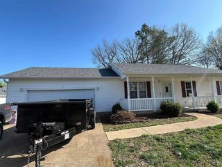White house with attached garage and trailer in the driveway