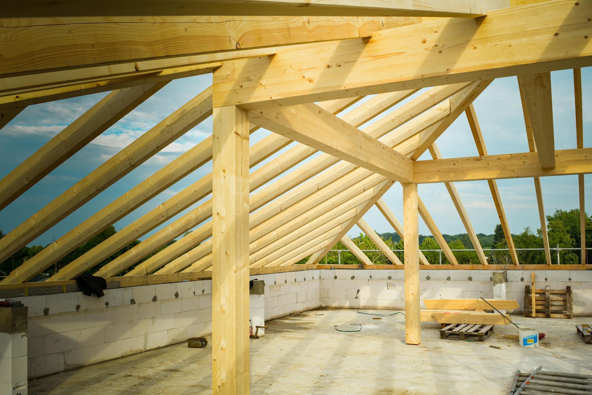Interior of a building under construction, showing wooden roof framing and beams.