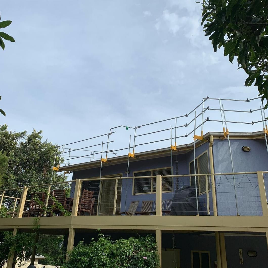 A Blue House with A Balcony and Scaffolding on The Roof — Site Safety NSW in Hunter Valley, NSW