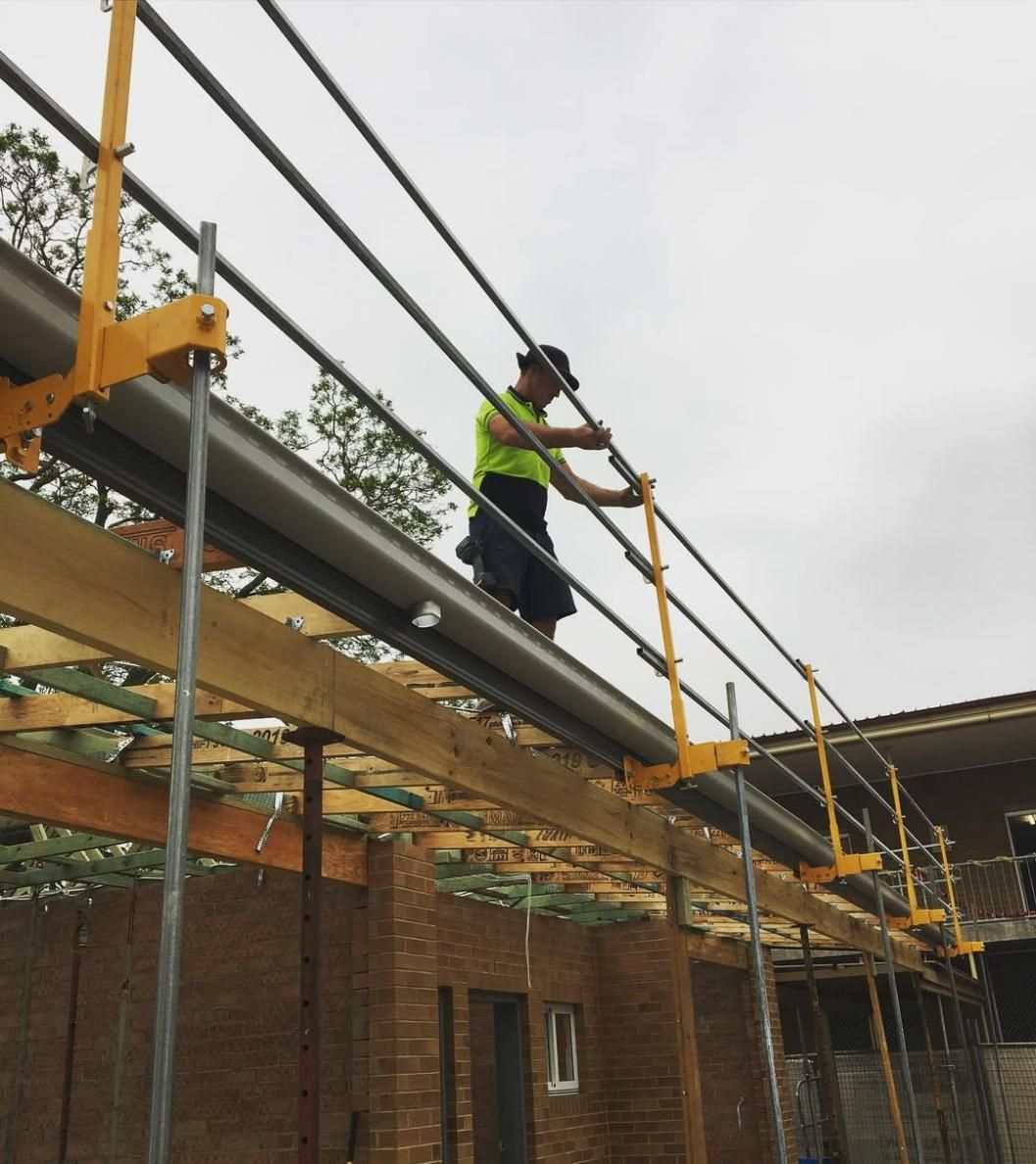 A Man in A Yellow Vest Is Standing on A Scaffolding — Site Safety NSW in Central Coast, NSW