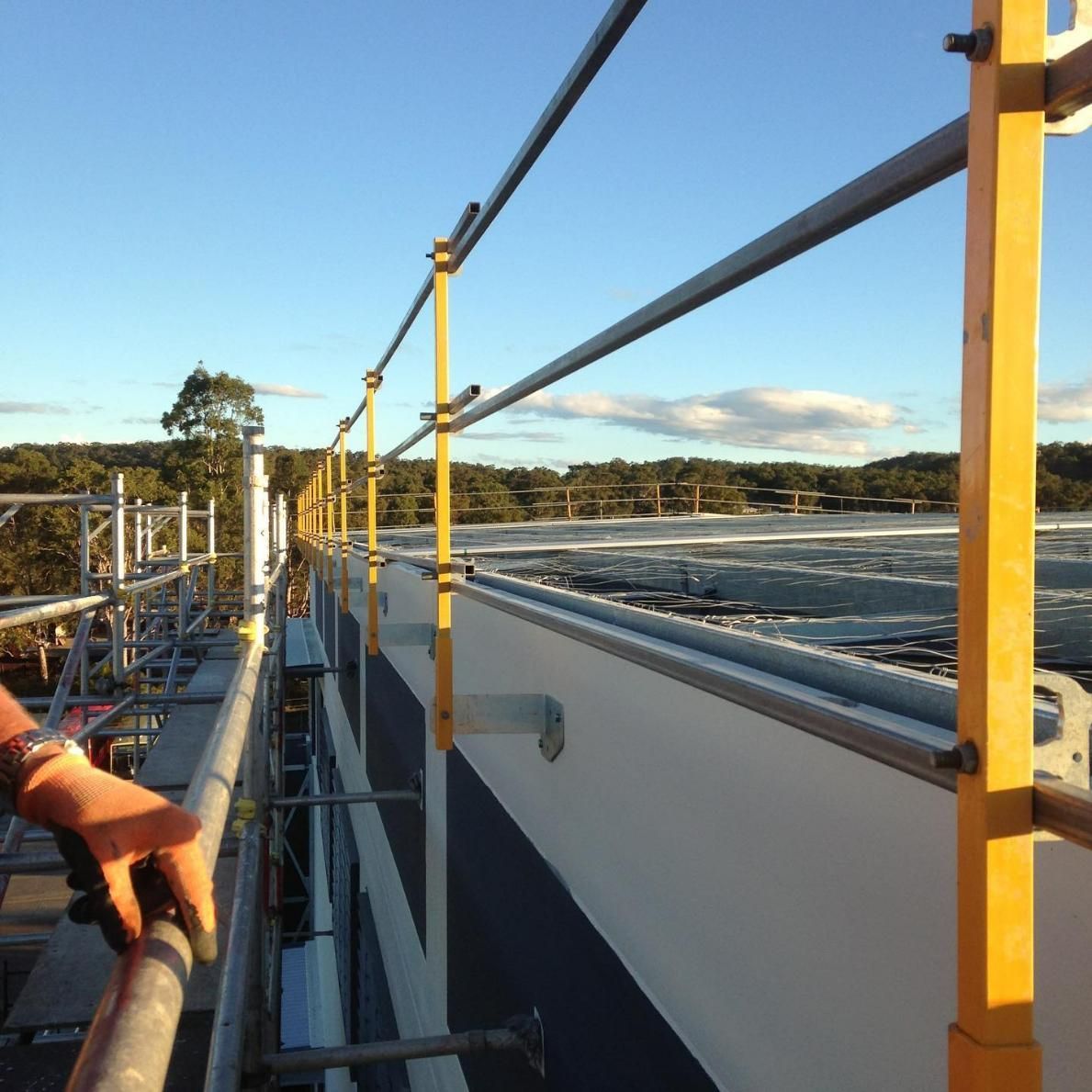 A Person Standing on A Scaffolding Overlooking a Building — Site Safety NSW in Central Coast, NSW